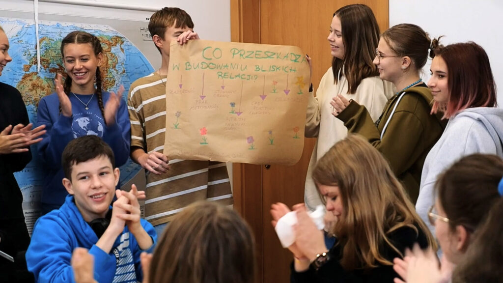 Uczniowie wspólnie omawiają plakat o budowaniu bliskich relacji.